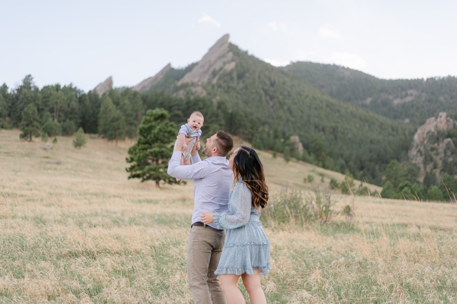 Father hold his son during a family portrait session in front of the Flatirons in Boulder Colorado.
