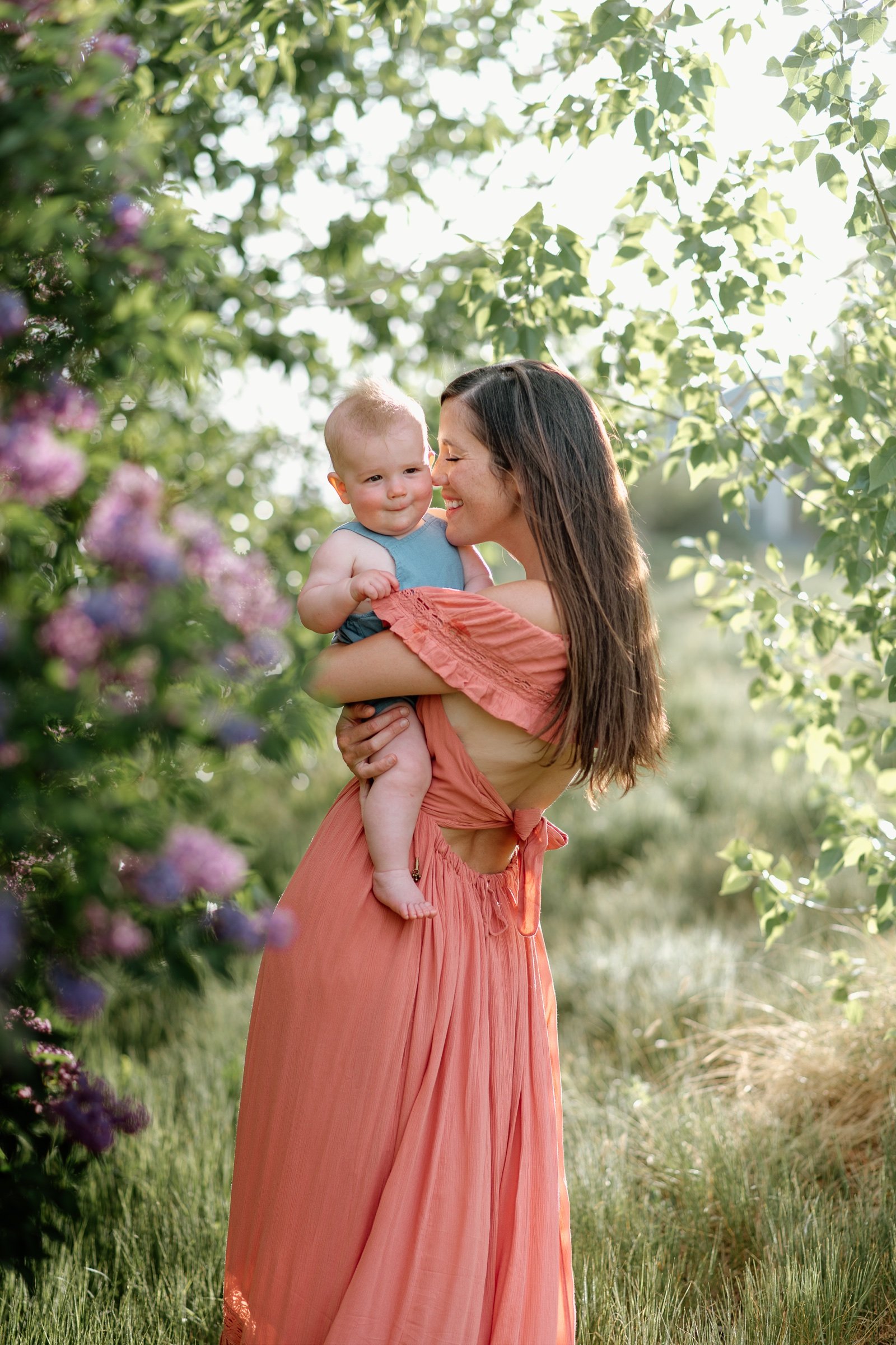 Mother wearing a pink dress snuggling her son during a photoshoot near Denver Colorado