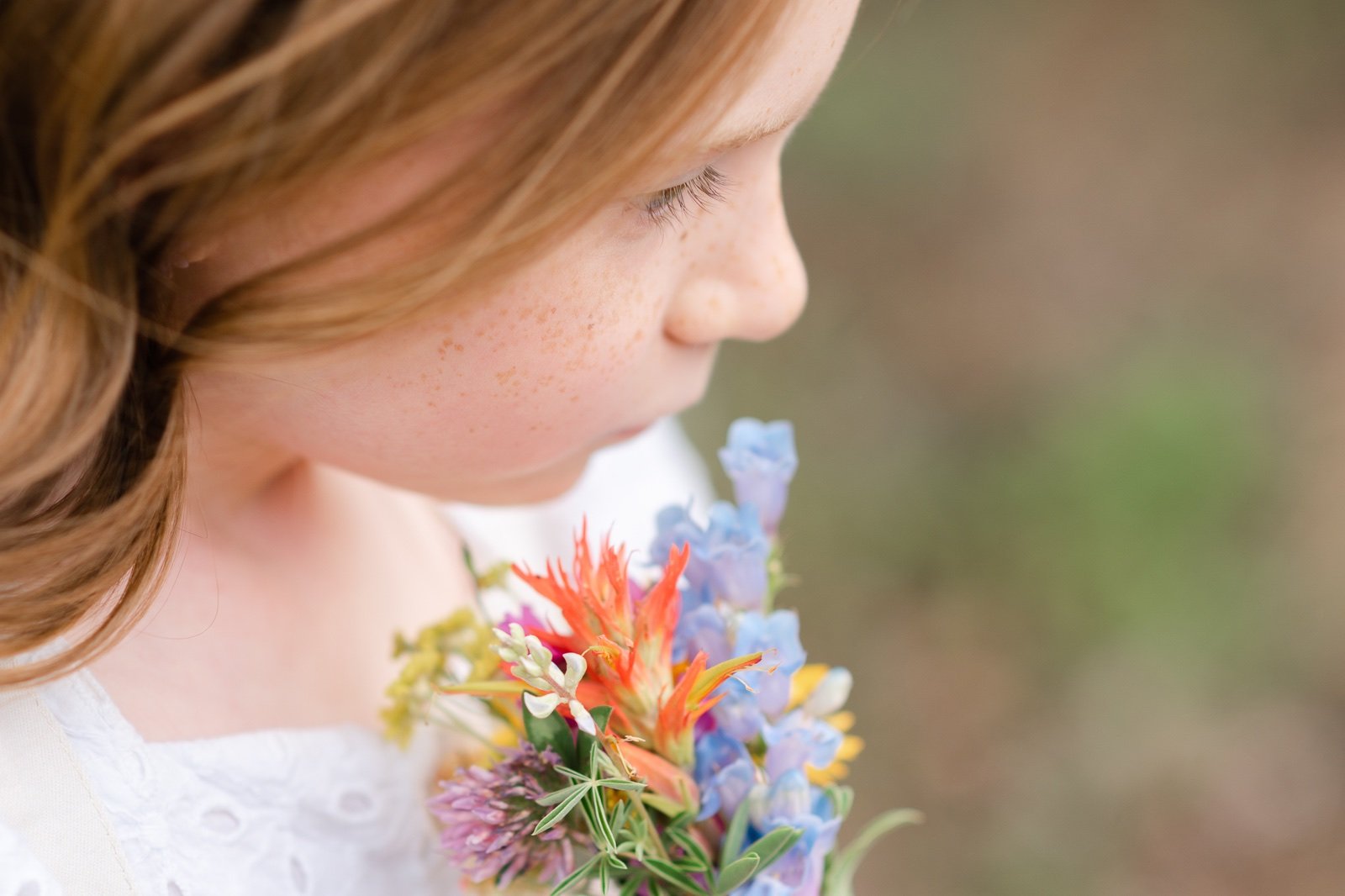 Young girl holding a small bouquet of wildflowers during a family portrait session in Colorado