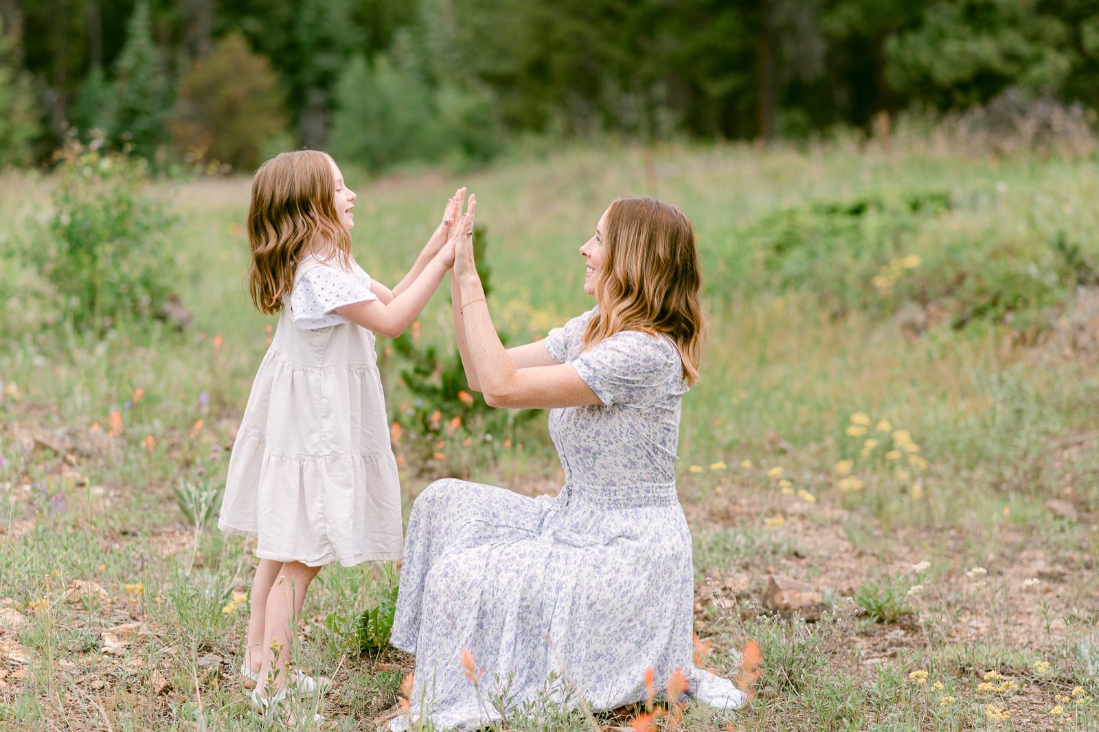 A portrait of a mother and daughter playing together in a meadow of wildflowers in Nederland Colorado