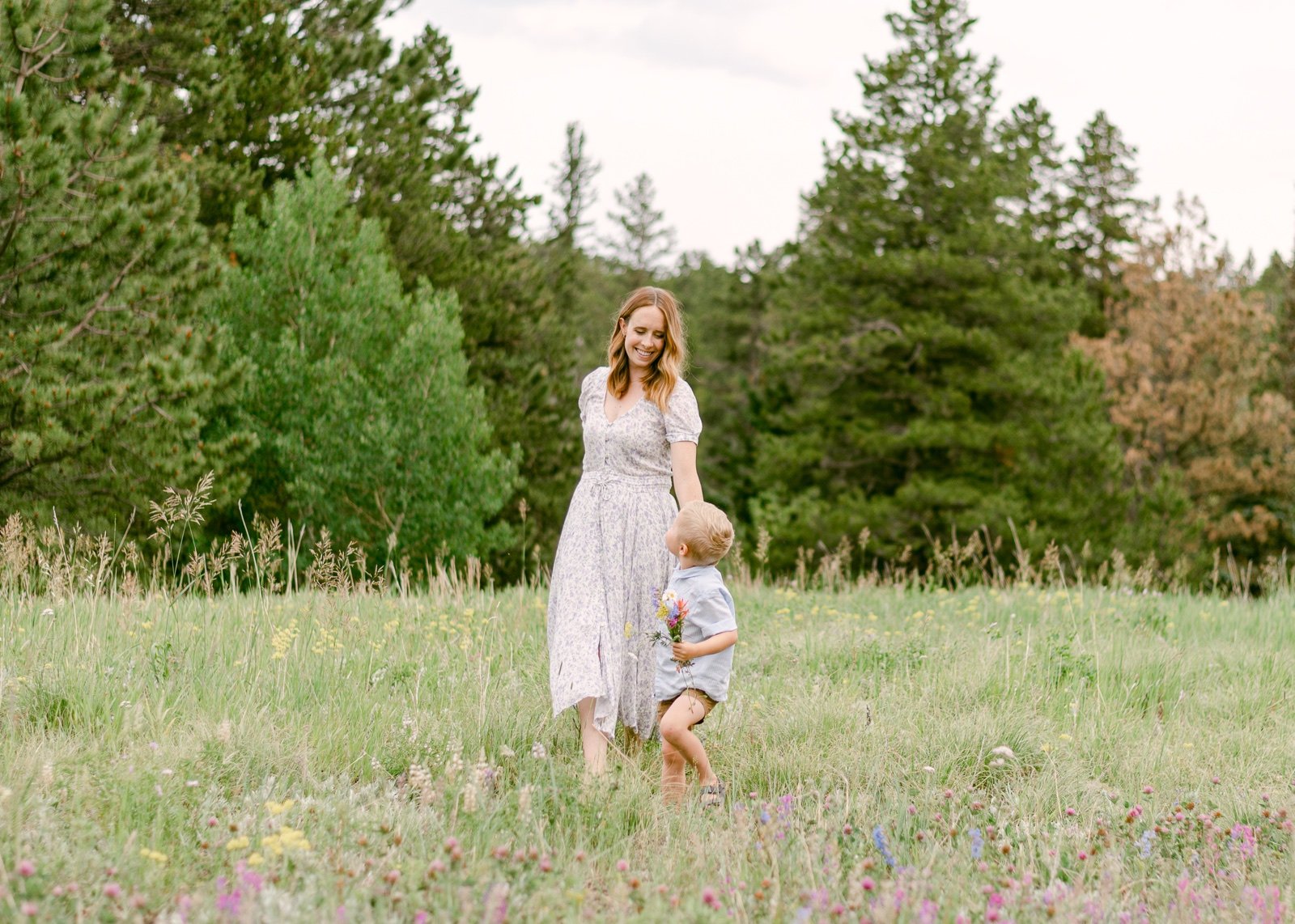 A portrait of a mother and son walking together in a meadow of wildflowers in Nederland Colorado