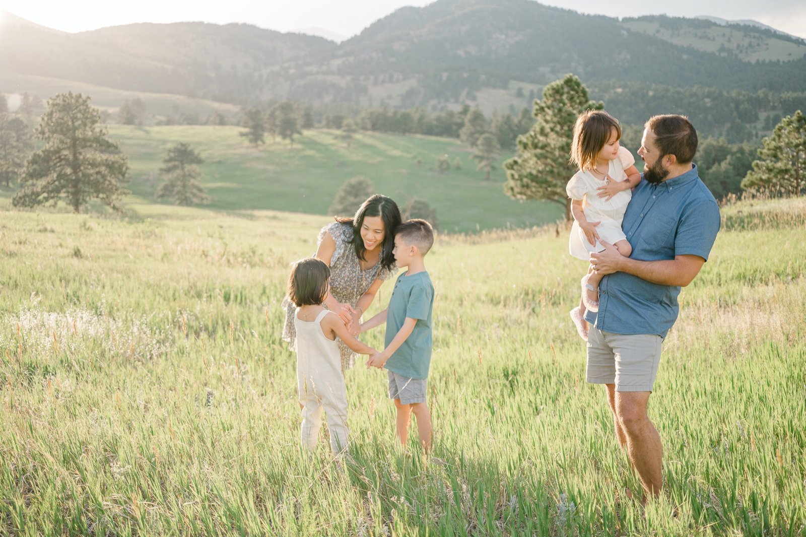 Golden Colorado family playing in a lush green mountain meadow at sunset