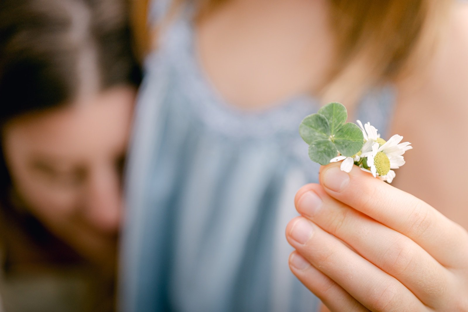 A daughter holding a four leaf clover during a family vegetable garden portrait session with Olive and Aster