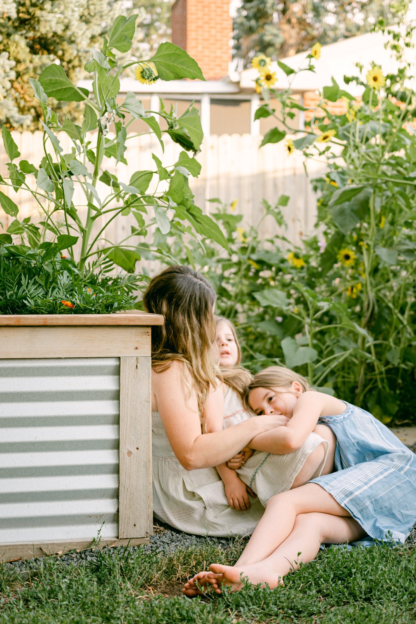 Mother and daughters playing in their family vegetable garden during a family portrait session with Olive and Aster