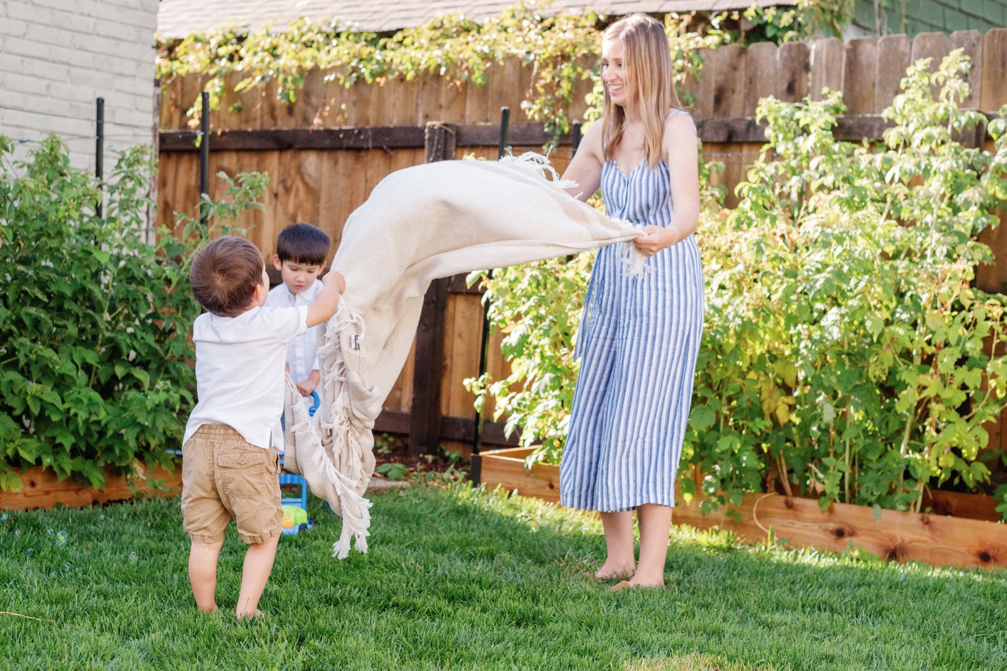 Mother and her sons playing parachute in their vegetable garden in Denver Colorado during a motherhood photoshoot