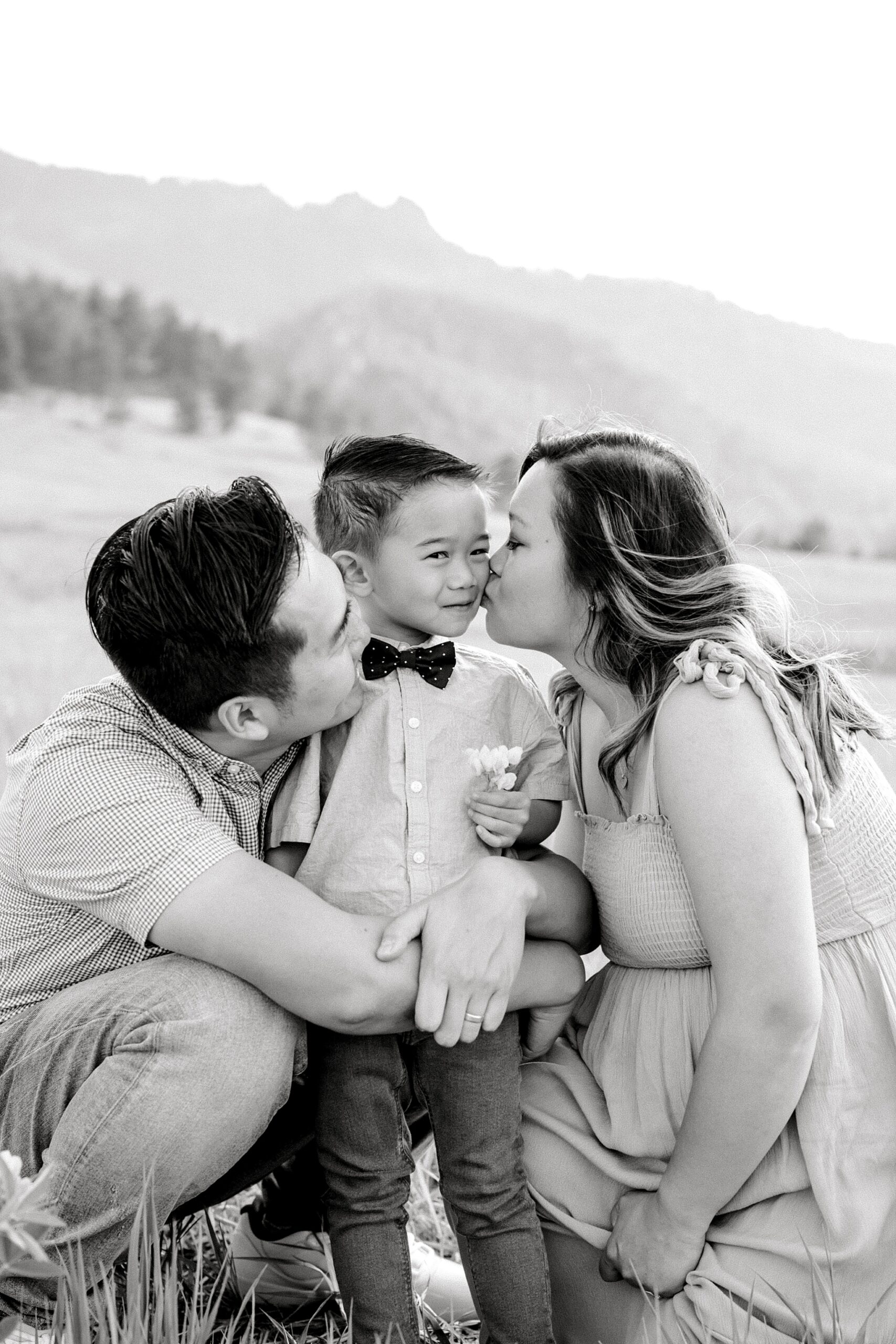 Family of three having their photos taken in Chautauqua Park in Boulder, Colorado with mom kissing her son
