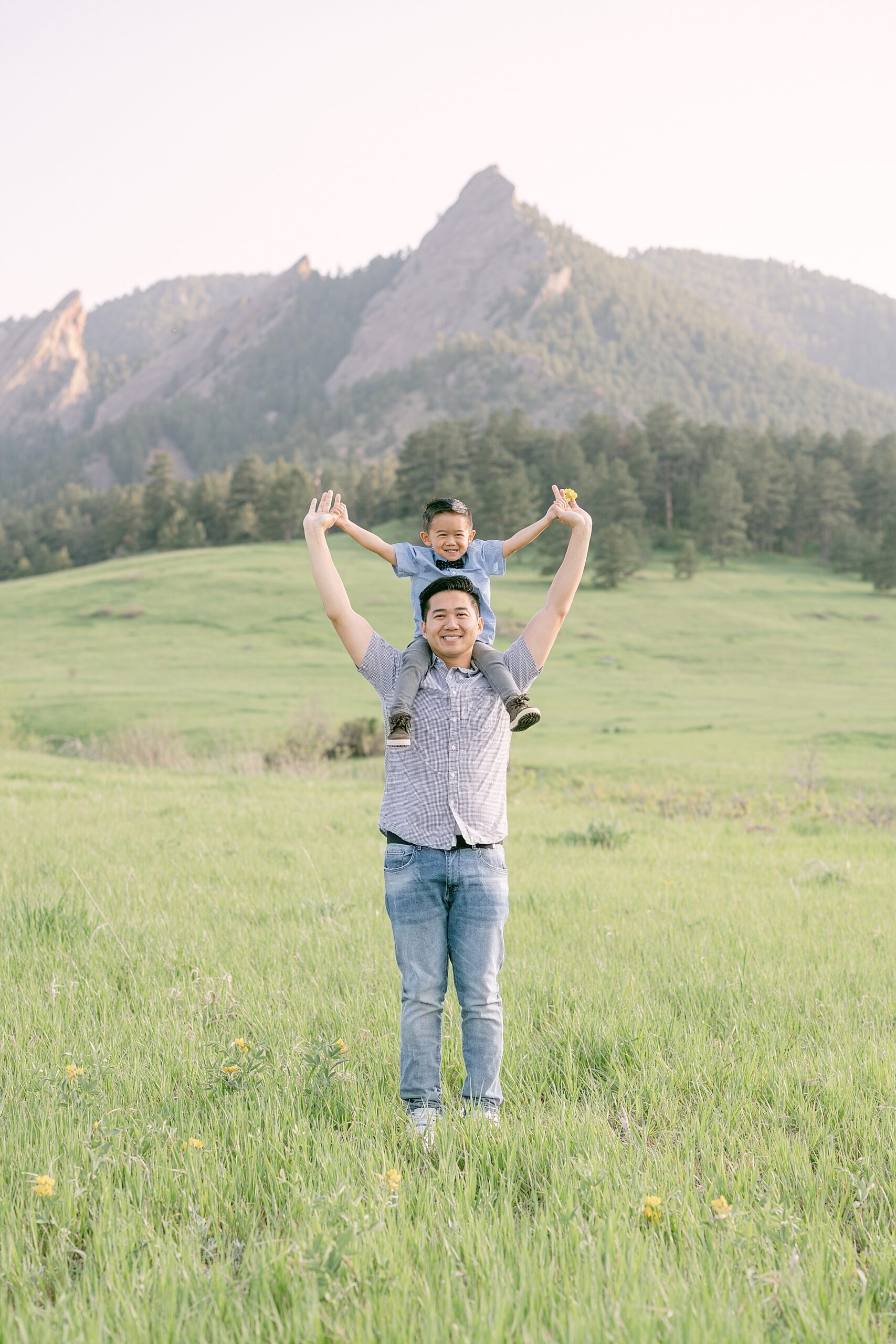 Young father giving his son a piggy back ride with the Colorado Flatirons in the background during an evening portrait session in Boulder.
