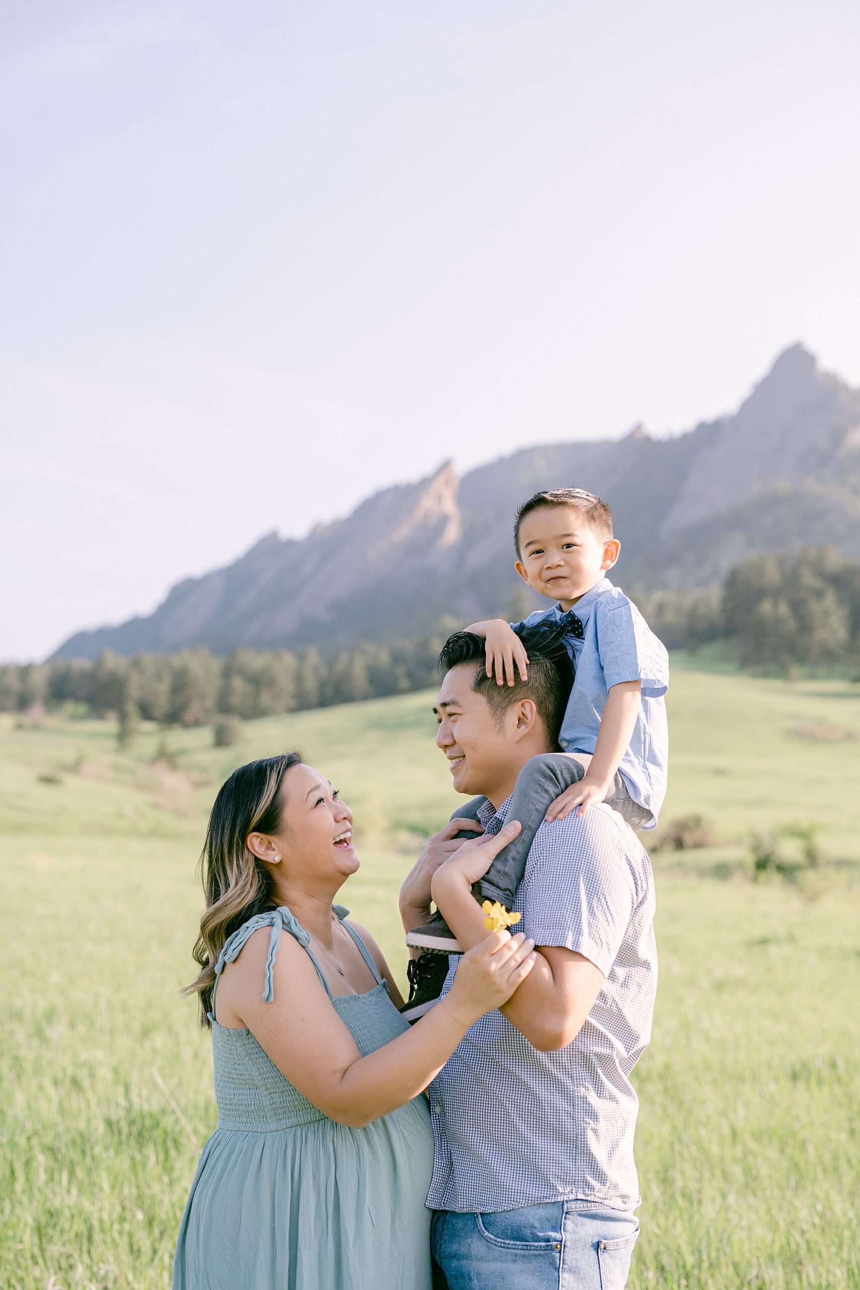 Family of three having their photos taken in Chautauqua Park in Boulder, Colorado with mountains in the background