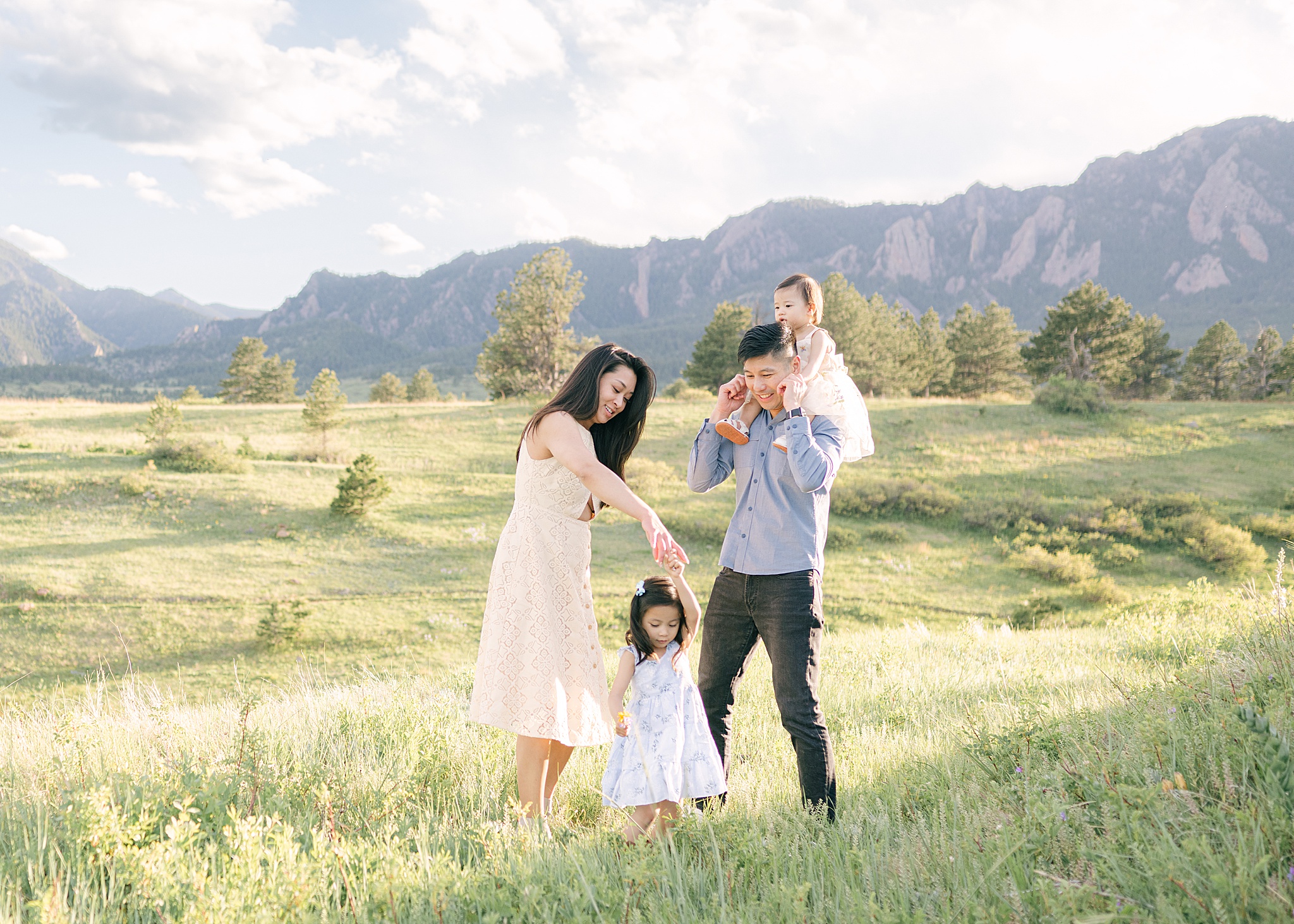 Two parents from Denver dancing with their daughters during a family photoshot in Boulder, CO with the mountains in the background