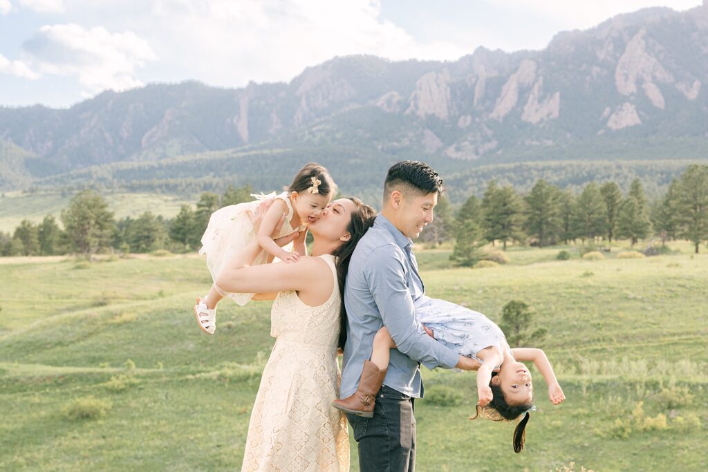 Two parents from Denver playing with their daughters during a family photoshot in Boulder, CO with the mountains in the background