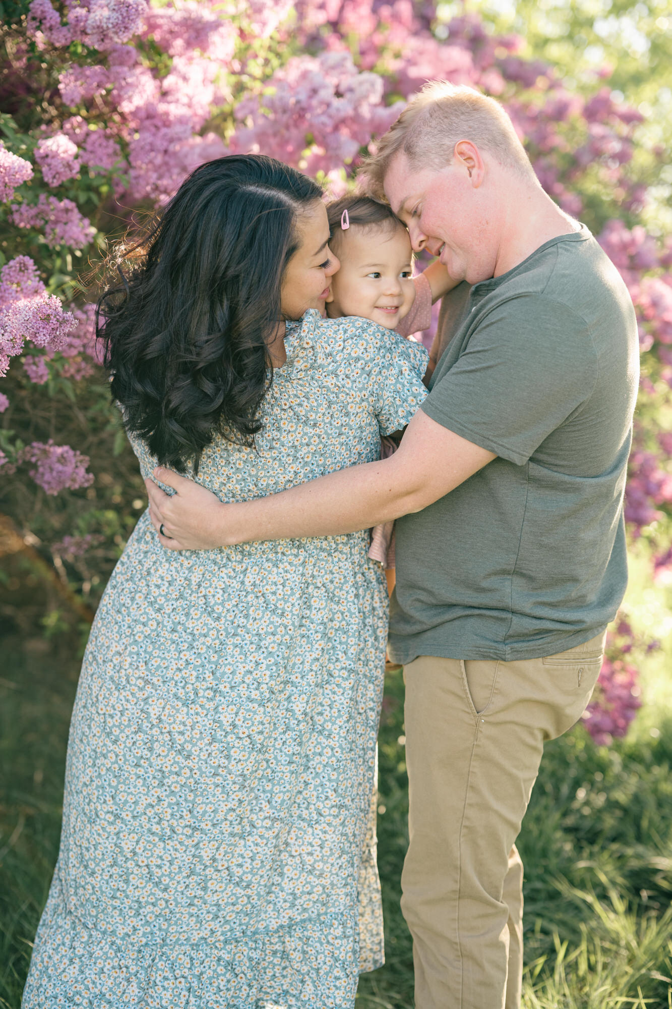 Spring Family Photos in Denver with a family of 3 hugging with purple lilacs in the background