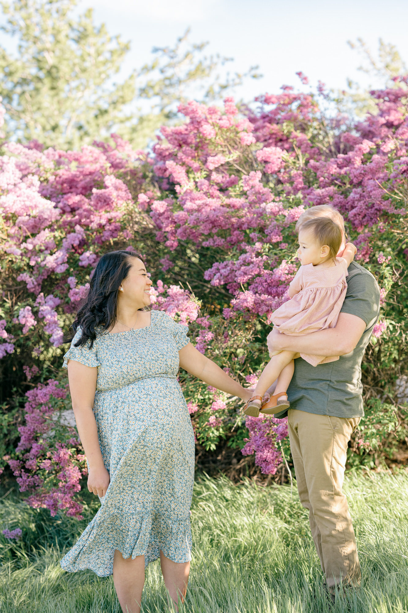 Spring Family Photos in Denver with a family of 3 playing with purple lilacs in the background