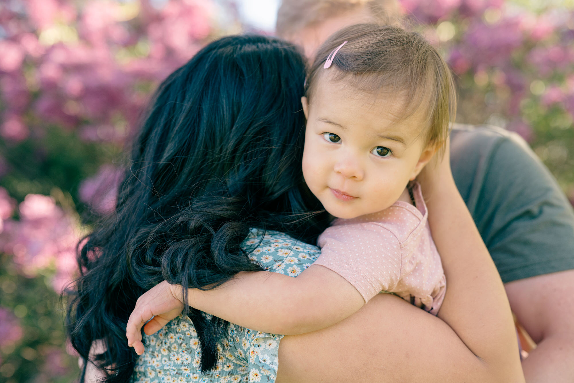 Spring Family Photos in Denver of a mom hugging her toddler purple flowers in the foreground