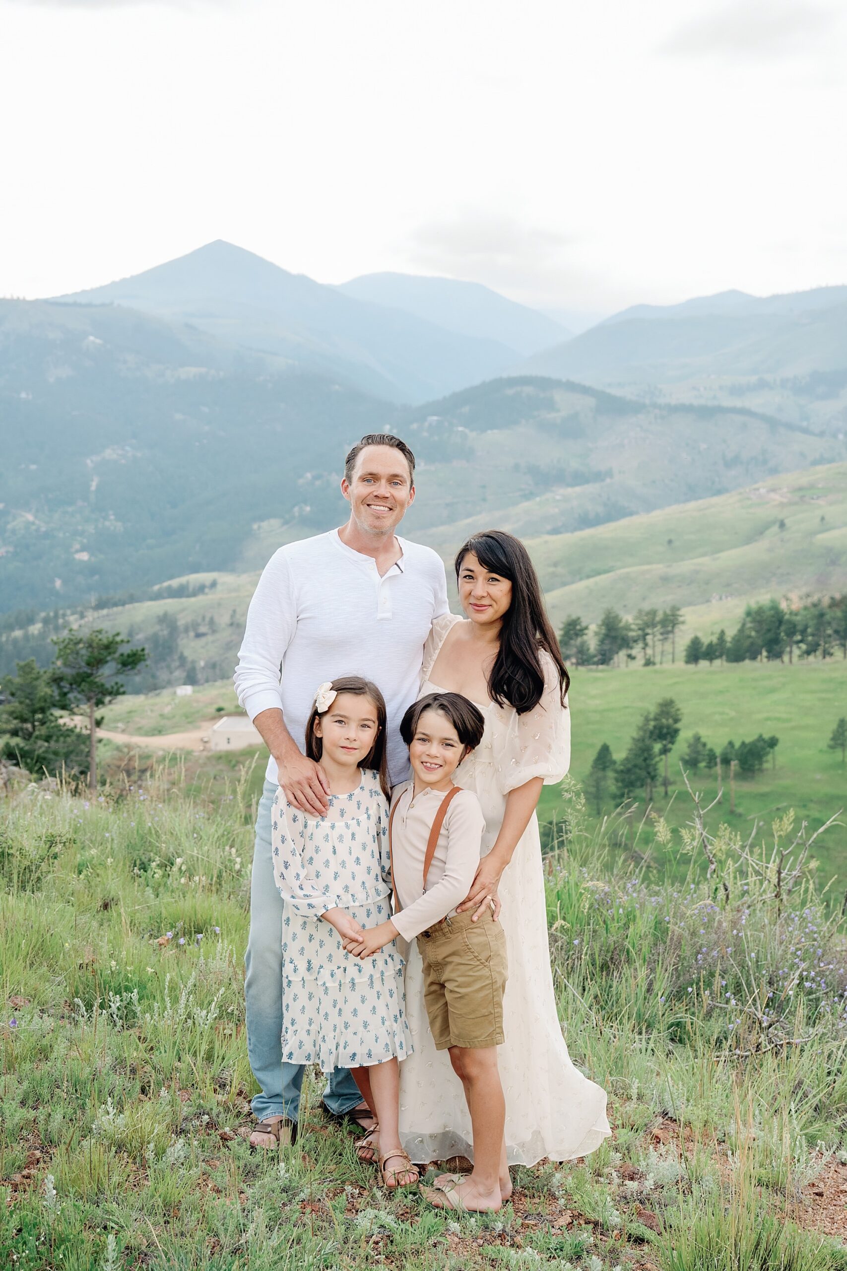 A traditional portrait of a family of four from Denver with mountains in the background taken a family photographer in Boulder Colorado